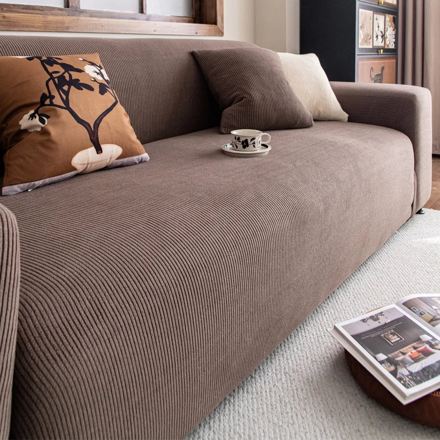 Close up of ribbed mocha brown corduroy sofa cover with cushions and a coffee cup