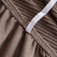 Detail of the elastic hem band tucking the mocha brown corduroy cover under the seat