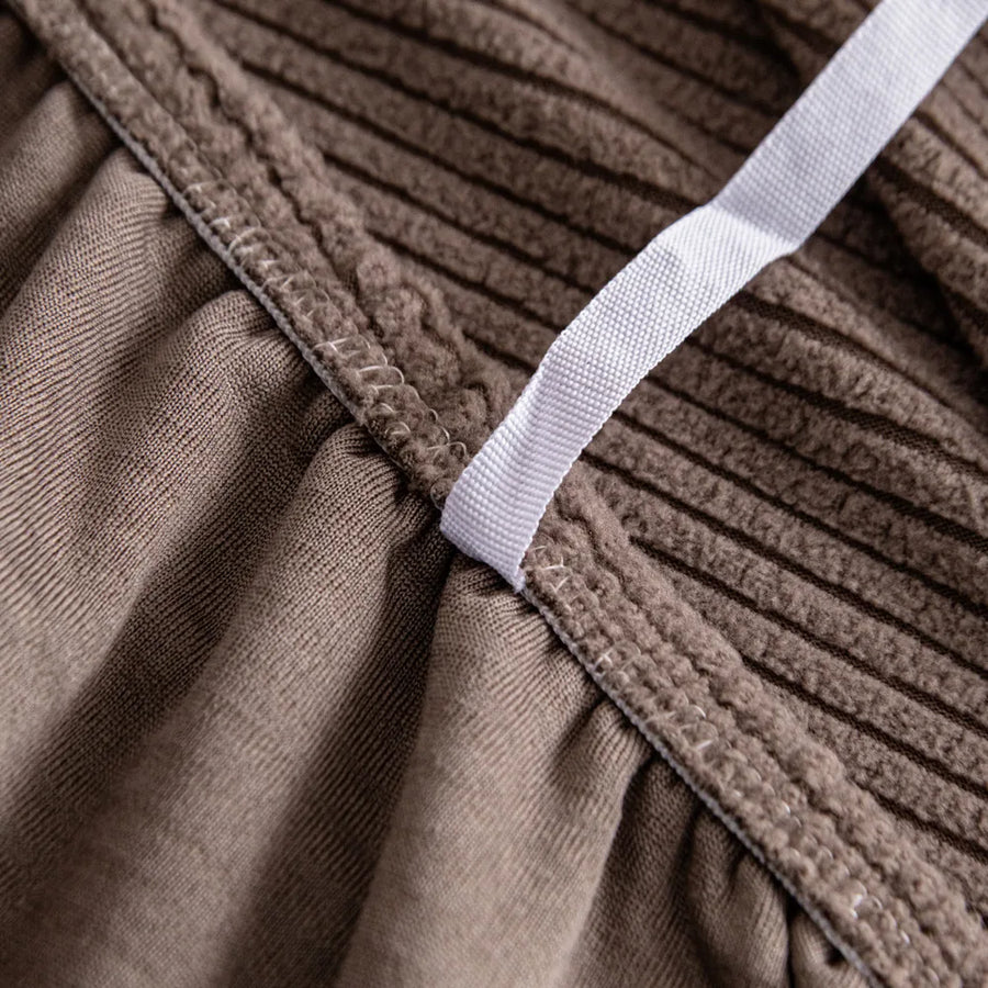 Detail of the elastic hem band tucking the mocha brown corduroy cover under the seat