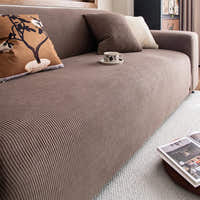 Angled view of mocha brown corduroy sofa cover with cushions and coffee cup on the seat
