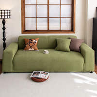 Olive green corduroy stretch sofa cover styled with a terracotta cushion by a wood framed window