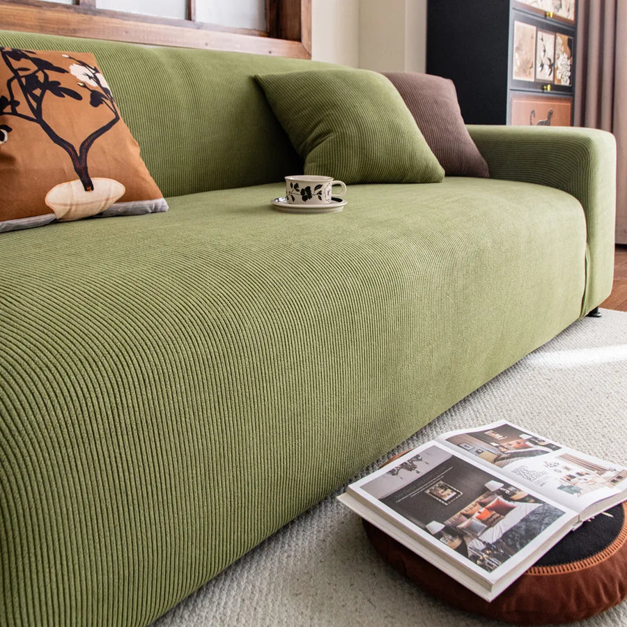 Close up of ribbed olive green corduroy sofa cover with a coffee cup on the seat