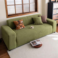 Olive green corduroy sofa cover in a warm living room with layered cushions and rug