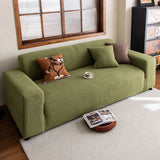 Olive green corduroy sofa cover in a warm living room with layered cushions and rug