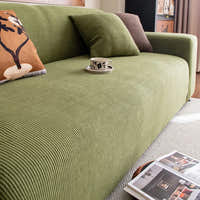 Angled detail of olive green corduroy sofa cover with a cushion and coffee cup