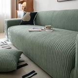 Close up of ribbed olive mist corduroy sofa cover with a book and coffee cup on the seat