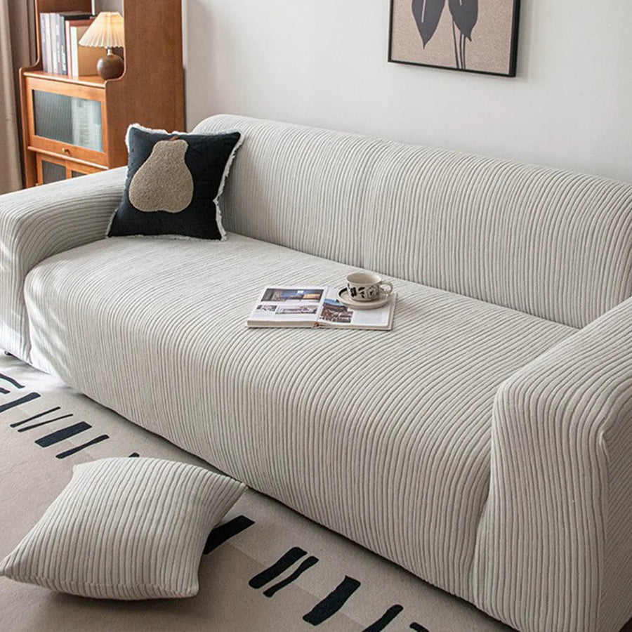 Silver Cloud corduroy sofa cover styled with a black accent cushion and an open magazine