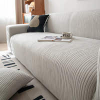 Angled view of the Silver Cloud corduroy sofa cover with a coffee cup and magazine on the seat