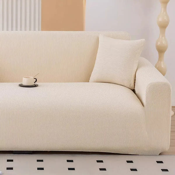 Warm beige corduroy stretch sofa cover in a bright room with a cushion and coffee cup