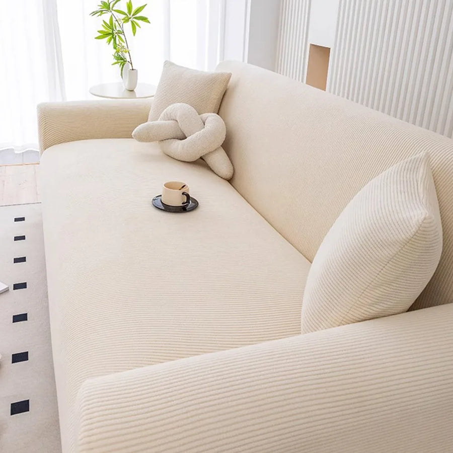 Angled view of warm beige corduroy sofa cover with a knot cushion and coffee cup