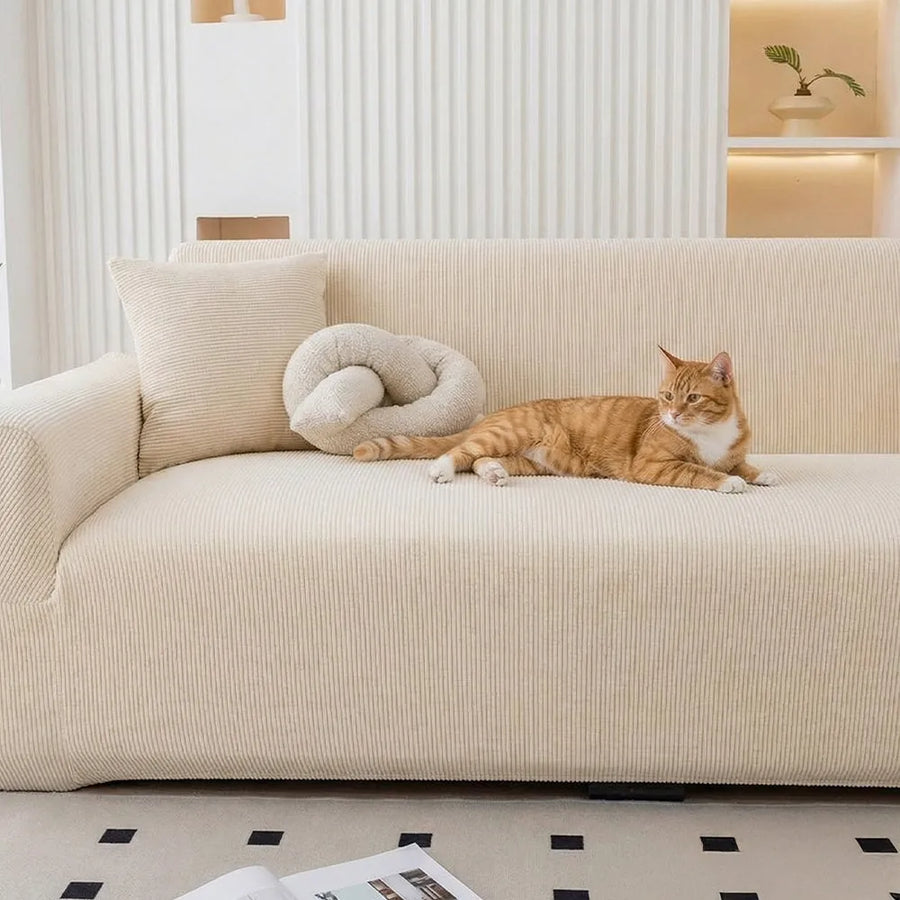 Ginger cat resting on a warm beige corduroy sofa cover beside a knot cushion