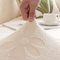 Hand lifting the Cream Petal floral cover to show its raised embossed flower texture