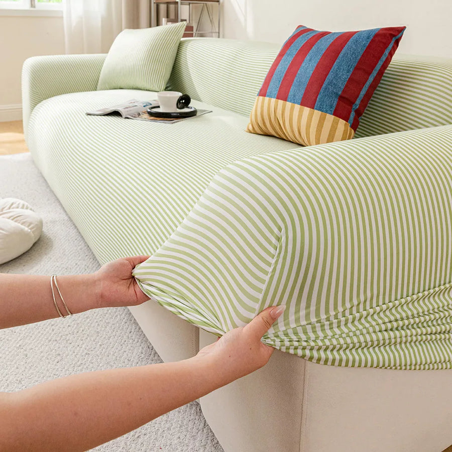 Hands stretching the Mint Breeze ice silk sofa cover snugly over a sofa armrest