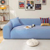 Blue striped ice silk sofa cover in a bright room with a gallery wall, an open magazine and a coffee cup