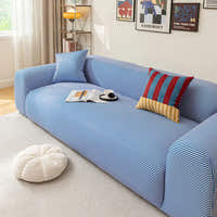 Angled view of the blue striped ice silk sofa cover, smooth stripes styled with an open magazine and coffee