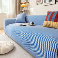 Corner view of the blue striped ice silk sofa cover with cushions and a floor pouf in a sunlit room