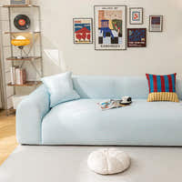 Light blue striped ice silk sofa cover in a bright room with a gallery wall, magazines and a coffee cup