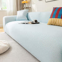 Angled view of the light blue striped ice silk sofa cover, smooth stripes styled with magazines and coffee