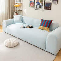 Light blue striped ice silk sofa cover styled beneath a poster gallery wall with cushions and a floor pouf
