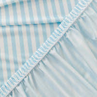 Close-up of the stretchy ruffled elastic hem trimming the underside of the light blue striped ice silk cover