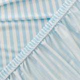 Close-up of the stretchy ruffled elastic hem trimming the underside of the light blue striped ice silk cover