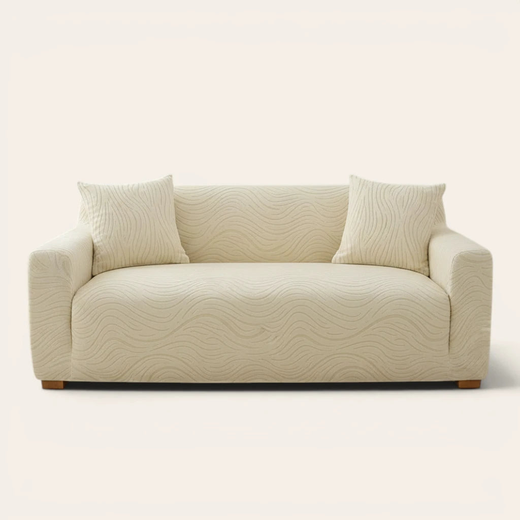 Cream beige jacquard sofa cover on a three-seater, front view on ivory backdrop with two matching cushions