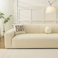 Cream beige jacquard sofa cover in a bright panelled living room with a cozy cushion and knot pillow