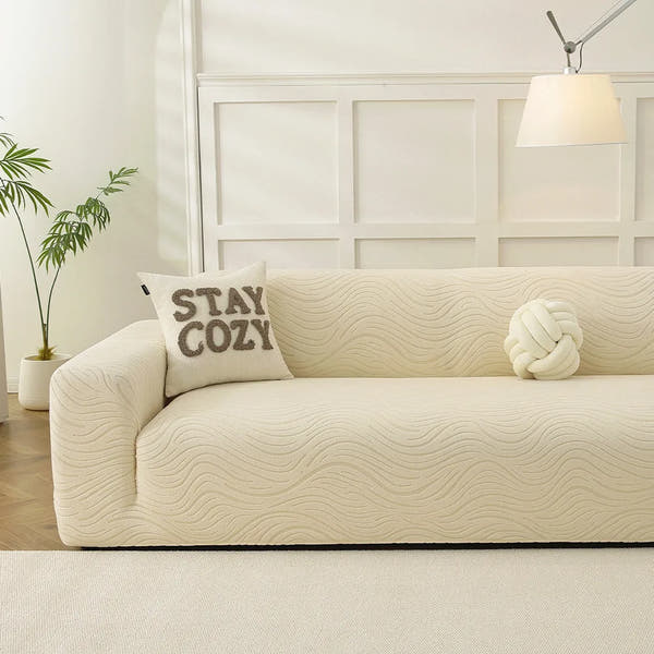 Cream beige jacquard sofa cover in a bright panelled living room with a cozy cushion and knot pillow