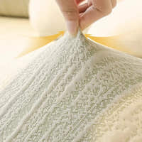 Hand lifting the cream ivory jacquard fabric to show its stretch, with a fine sage-flecked knit pattern