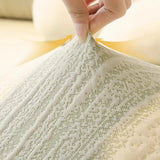 Hand lifting the cream ivory jacquard fabric to show its stretch, with a fine sage-flecked knit pattern