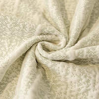 Macro of the cream ivory jacquard weave flecked with sage green, showing its delicate knit-like texture
