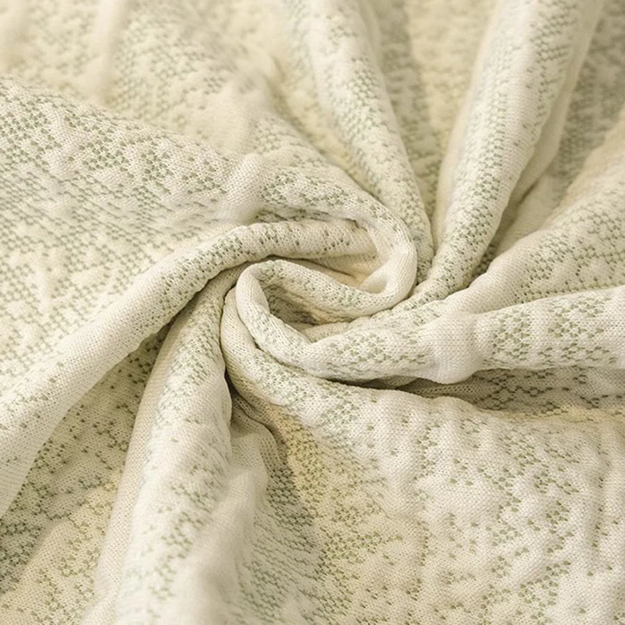 Macro of the cream ivory jacquard weave flecked with sage green, showing its delicate knit-like texture
