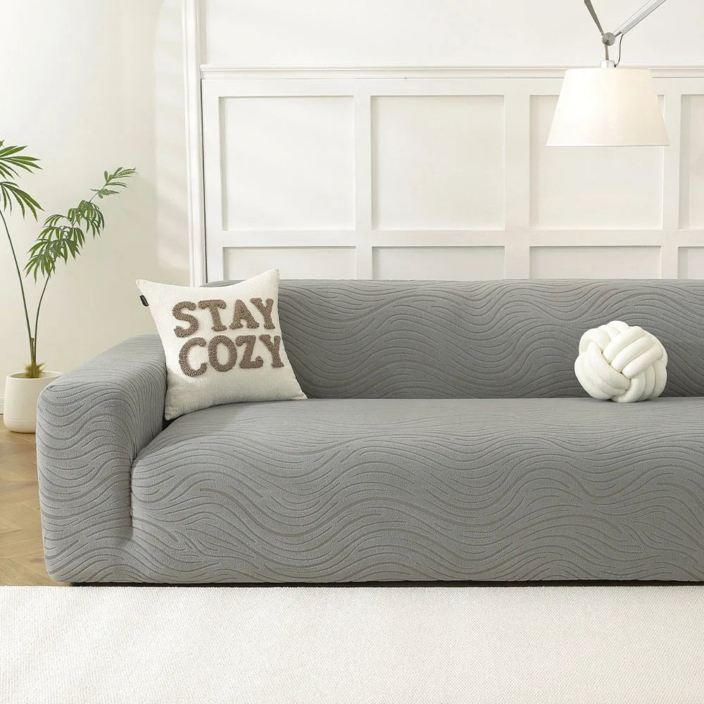 Mist grey jacquard sofa cover in a bright panelled living room with a cozy cushion and knot pillow