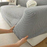 Hands fitting the mist grey jacquard cover over a seat cushion, showing its stretchy snug fit