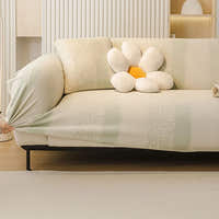 Hand stretching the cream sage striped jacquard cover over a sofa, showing its snug elastic fit