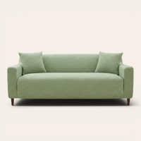 Sage green jacquard sofa cover on a three-seater, front view on ivory backdrop with two matching cushions