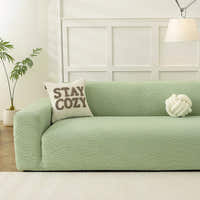 Sage green jacquard sofa cover in a bright panelled living room with a cozy cushion and knot pillow