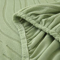 Close-up of the stretchy elasticated hem tucking the sage green jacquard cover under the sofa