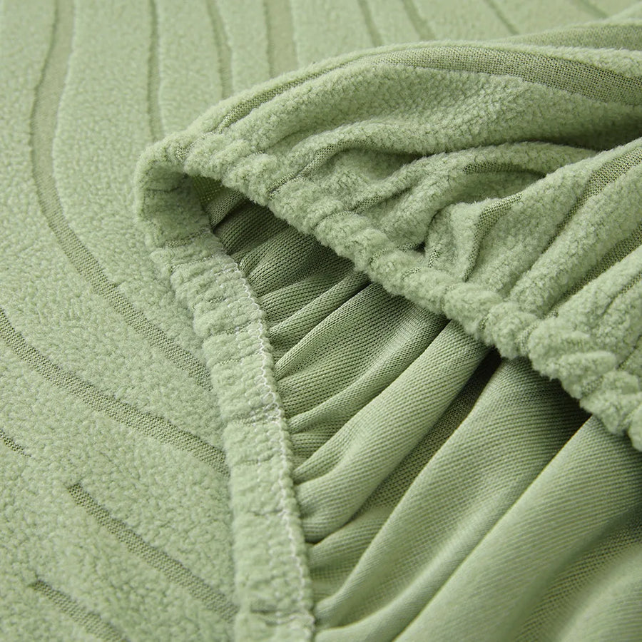 Close-up of the stretchy elasticated hem tucking the sage green jacquard cover under the sofa
