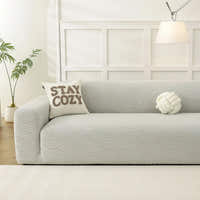 Soft ivory jacquard sofa cover in a bright room with STAY COZY cushion and knot pillow