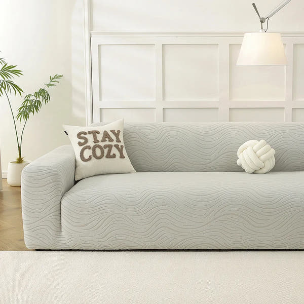 Soft ivory jacquard sofa cover in a bright room with STAY COZY cushion and knot pillow