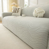 Angled close-up of soft ivory jacquard sofa cover showing wave texture and coffee cup