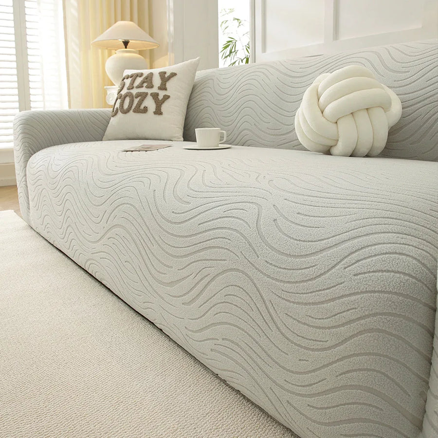 Angled close-up of soft ivory jacquard sofa cover showing wave texture and coffee cup