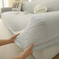 Hands stretching the soft ivory jacquard cover over an armrest to show its elasticity