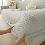 Hands stretching the soft ivory jacquard cover over an armrest to show its elasticity