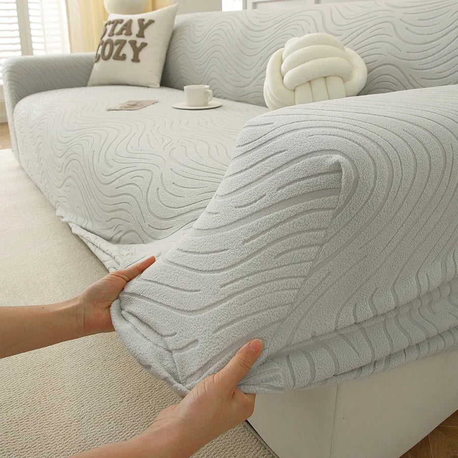Hands stretching the soft ivory jacquard cover over an armrest to show its elasticity