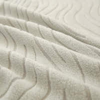 Macro of soft ivory jacquard fabric showing raised wave pattern and plush surface