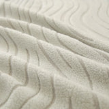 Macro of soft ivory jacquard fabric showing raised wave pattern and plush surface