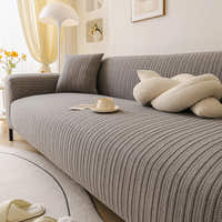 Angled seat view of the charcoal ribbed knit cover with a knot cushion, cup and floor lamp.