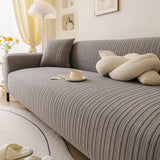 Angled seat view of the charcoal ribbed knit cover with a knot cushion, cup and floor lamp.